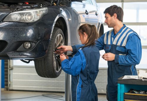 Mechanic teaching an intern the best practice. Learning on the job during a practical internship in a garage